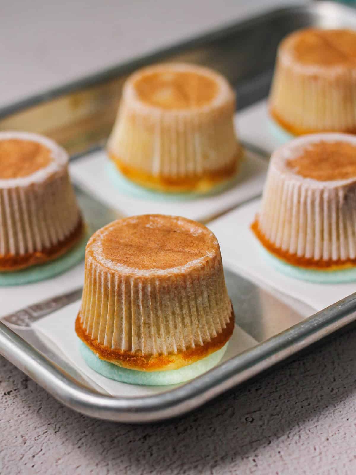 Process shot of cupcakes upside down on a baking sheet with wax paper for hot air balloon cupcakes.