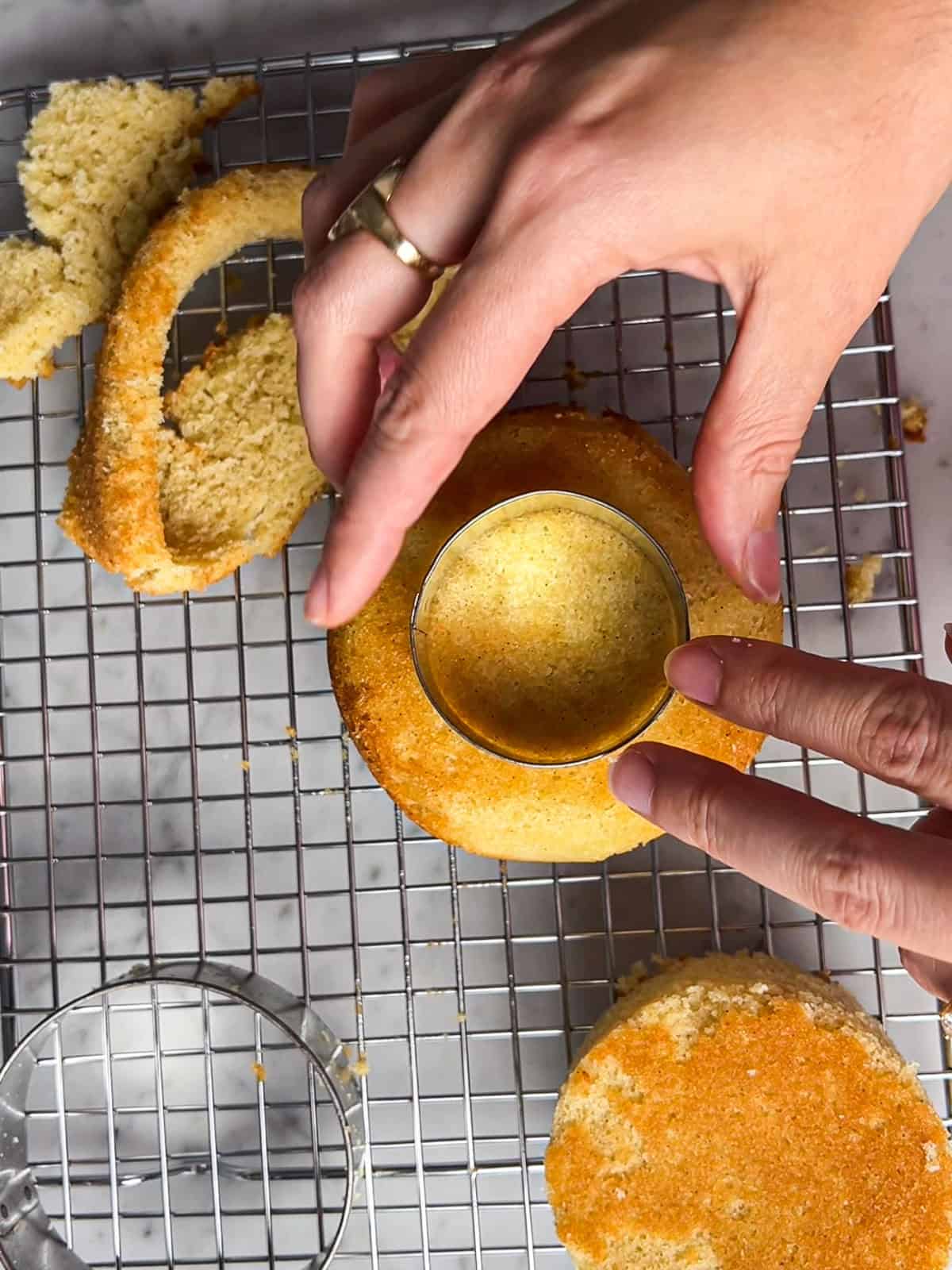 Using a cookie cutter to cut a 2" cake layer from a 4" layer of cake.