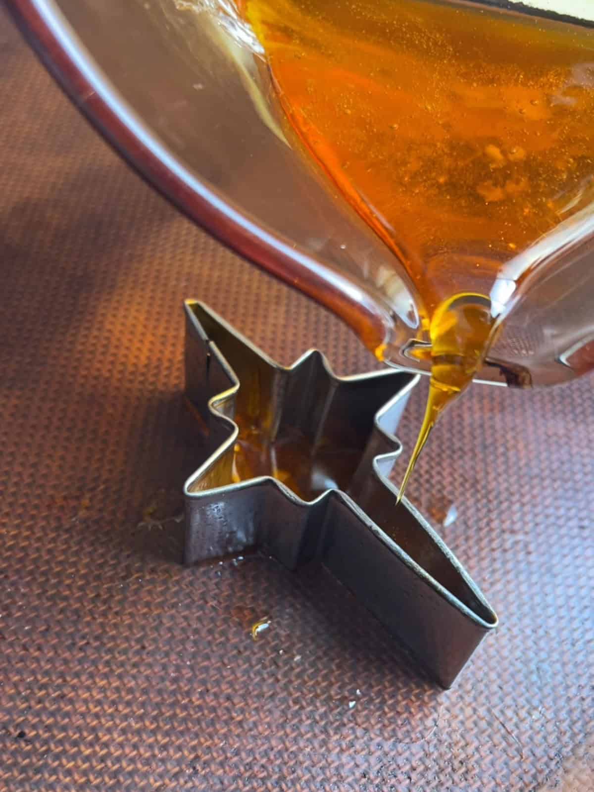 Pouring gold isomalt into a star cookie cutter.