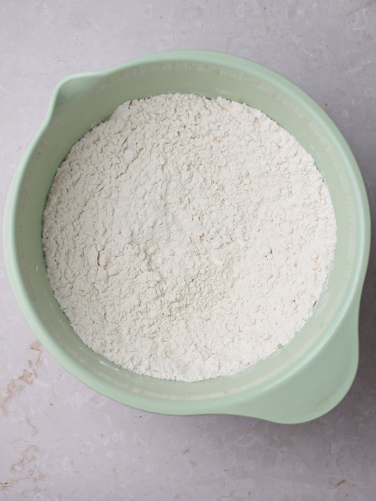 Flour and dry ingredients in a green mixing bowl, ready for baking.