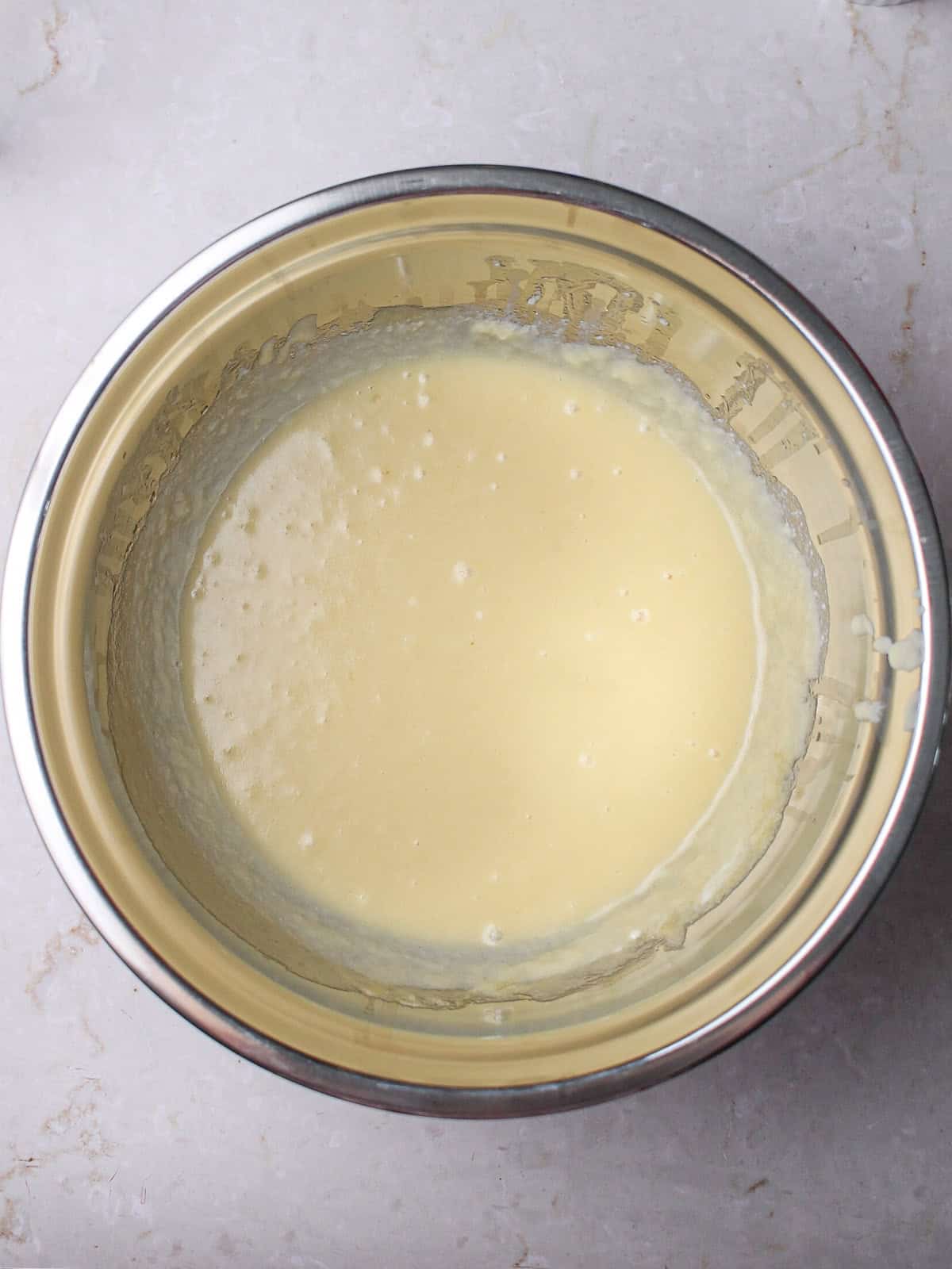 Wet ingredients for muffins in a silver mixing bowl.