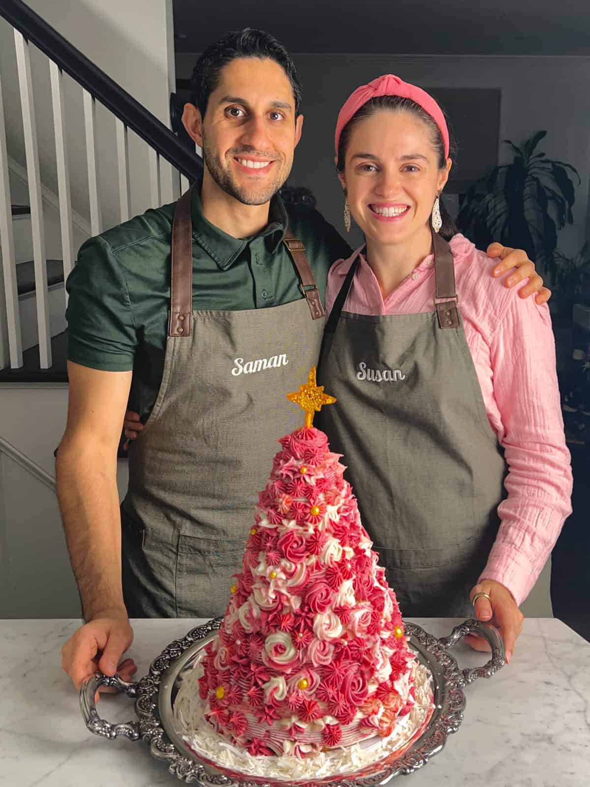 Susan and Saman posing with their pink 3D Christmas tree cake that they remade at home.