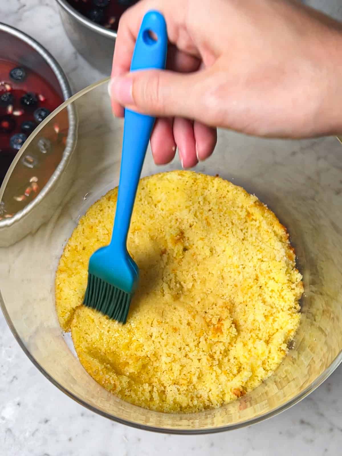 Brushing orange cake layer with glaze.
