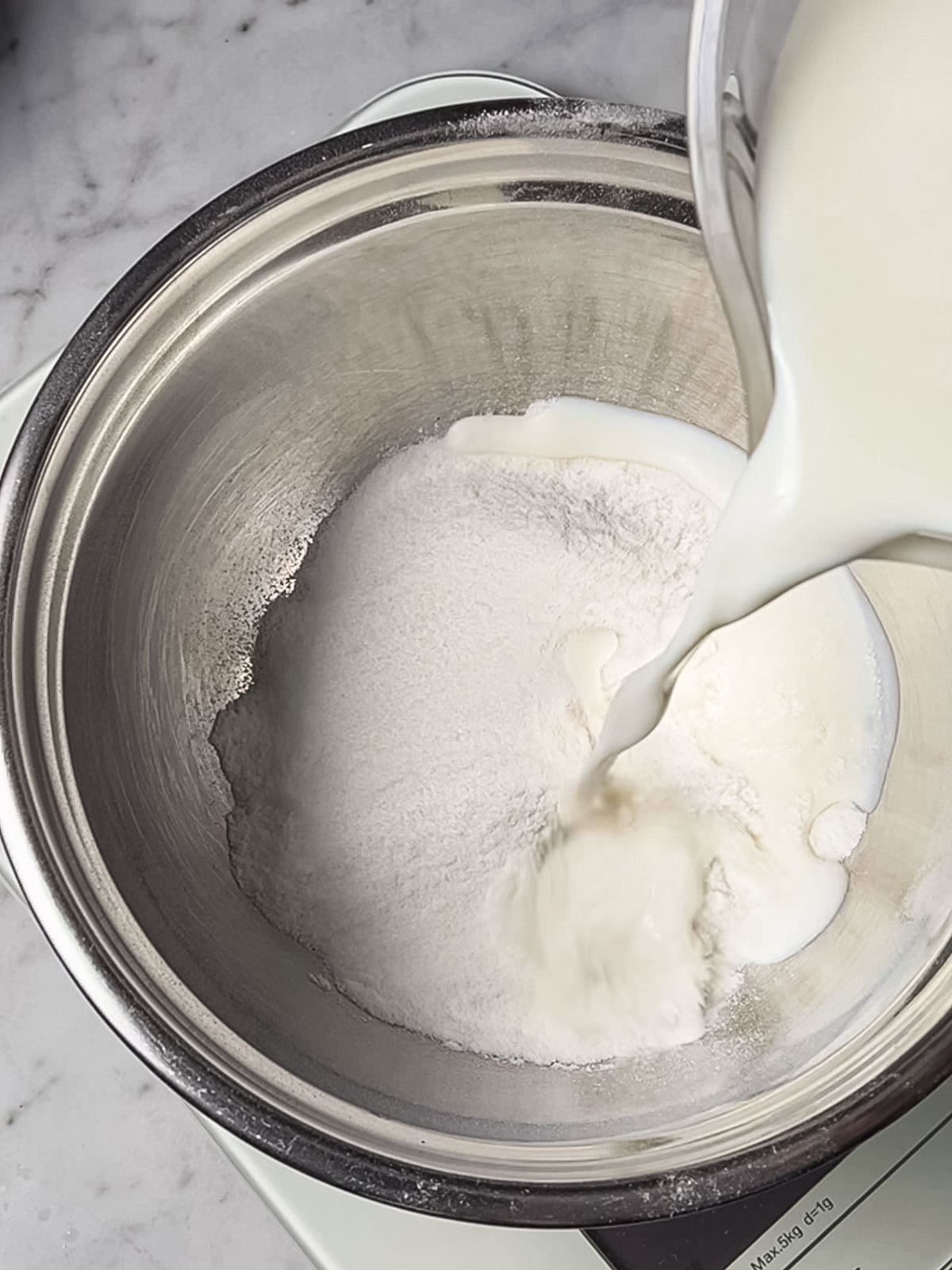 Adding cold milk to bowl of sifted rice flour.