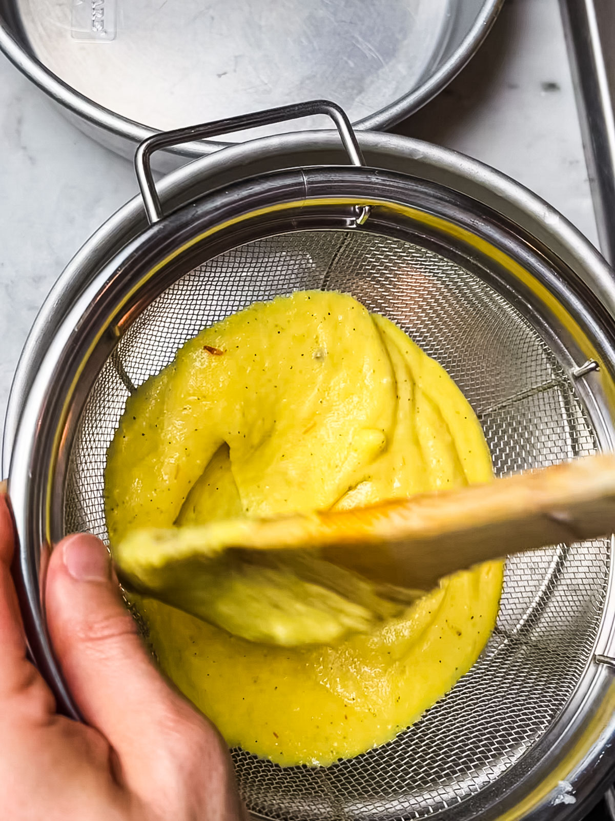 Putting saffron phirni through a strainer for smoothness.