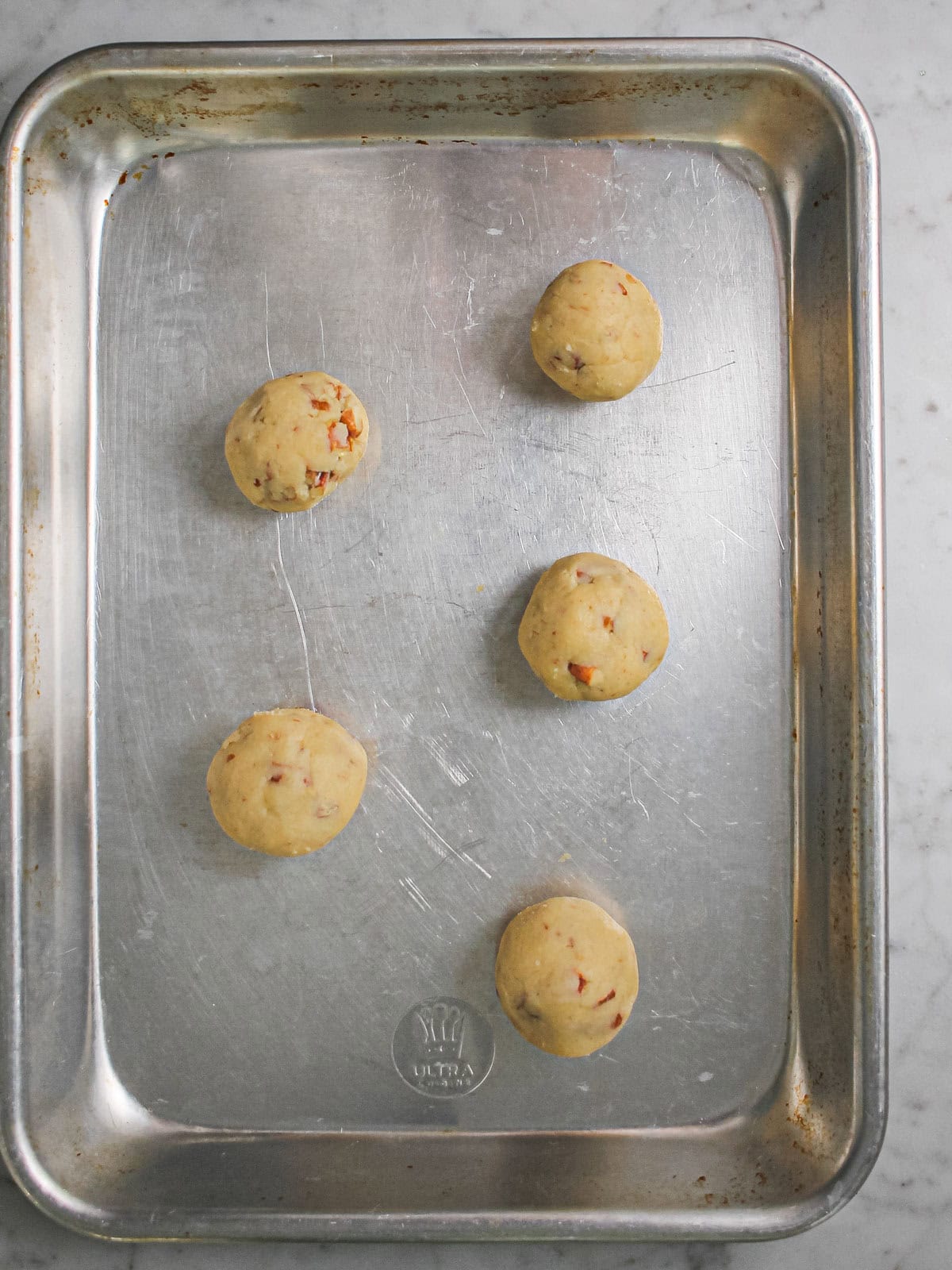 Overhead shot of rounded, unbaked balls of cookie dough.