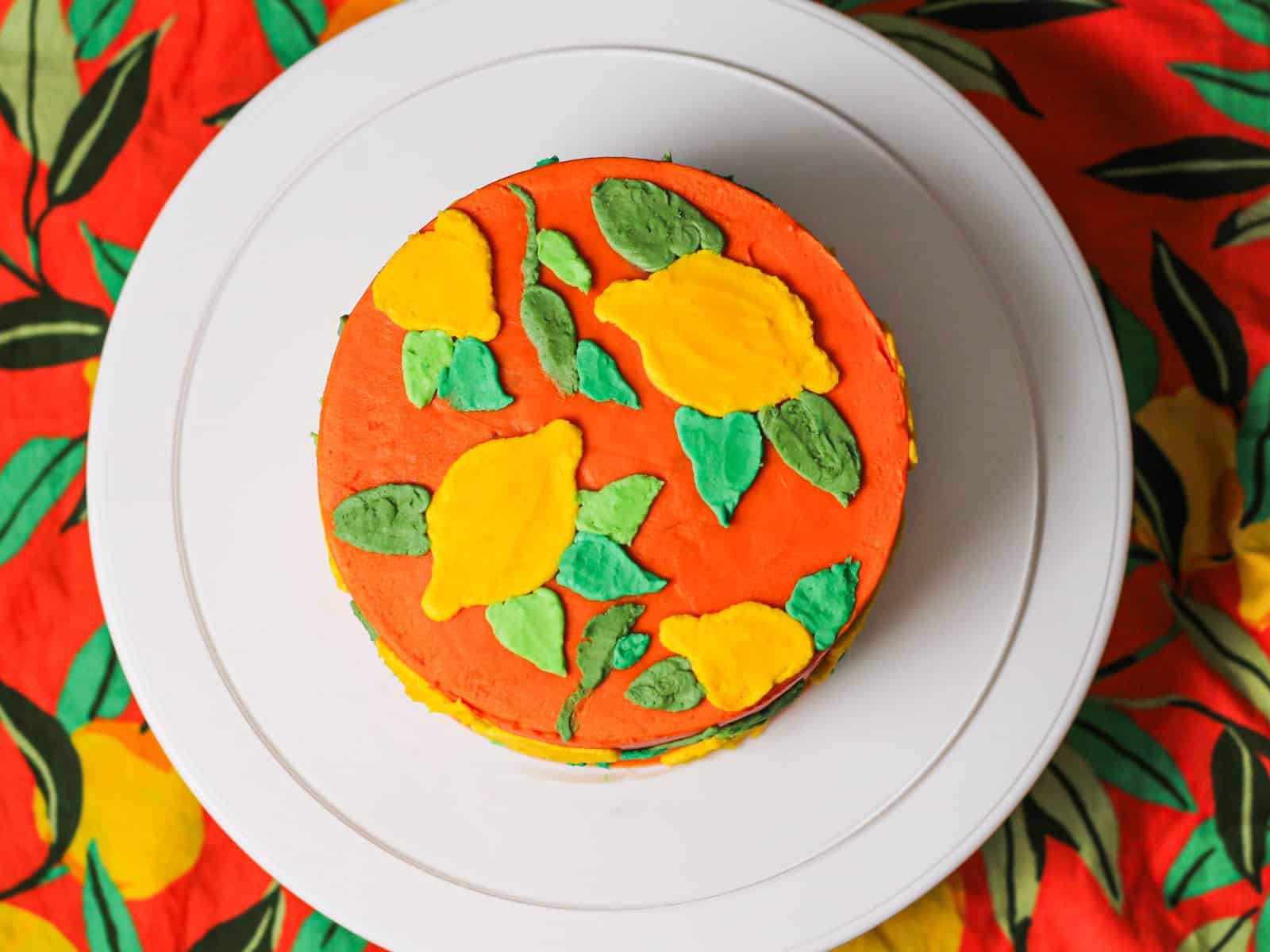 Vibrant orange layered cake decorated with colorful leaves for this buttercream lemon cake tutorial.