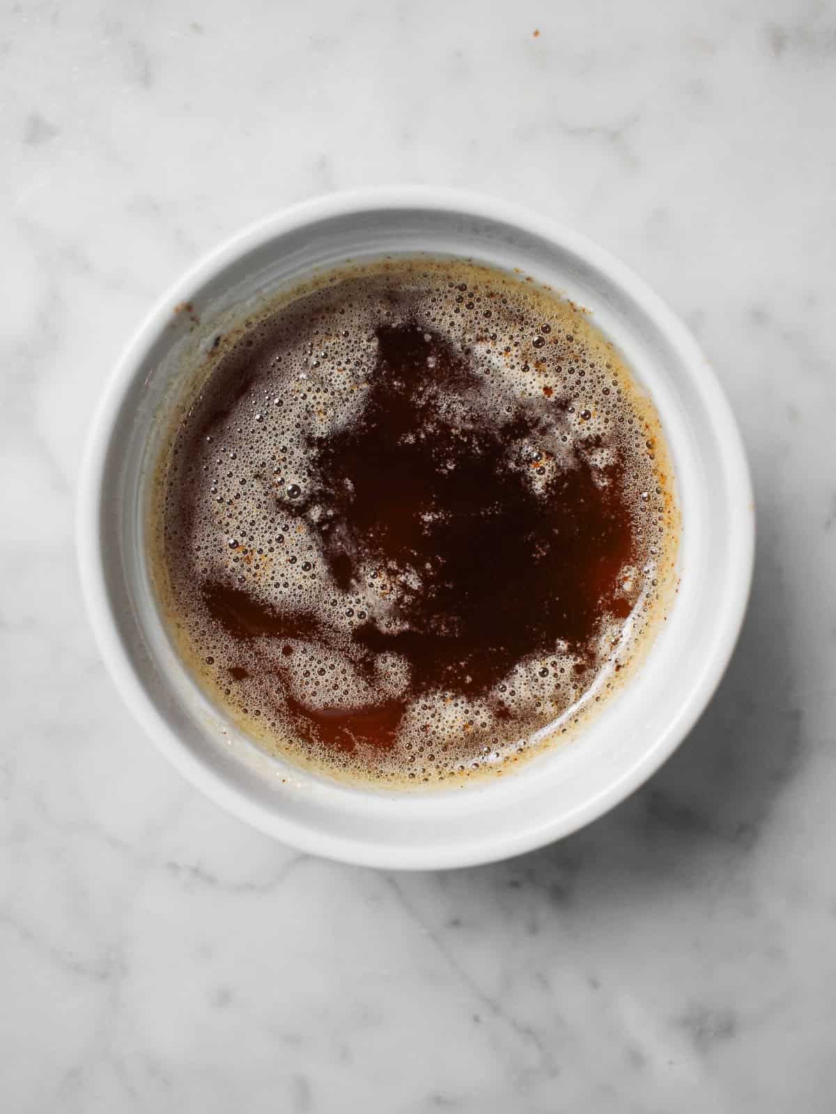 Golden brown butter with toasted flecks in a white ramekin.