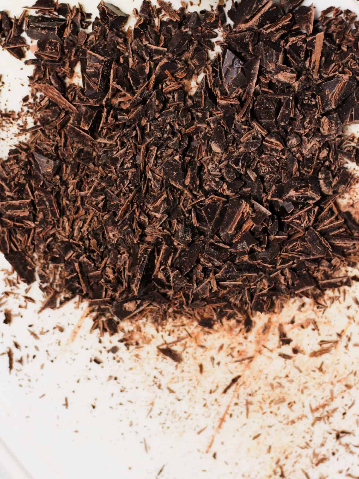 Roughly chopped dark chocolate bar on a cutting board.