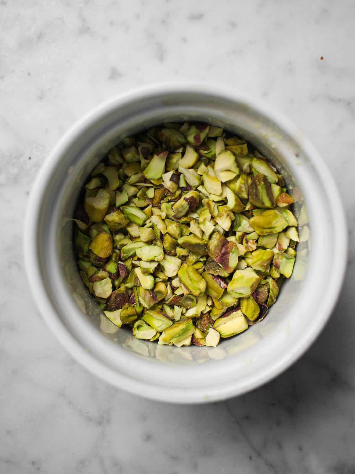Chopped pistachios in a white ramekin.