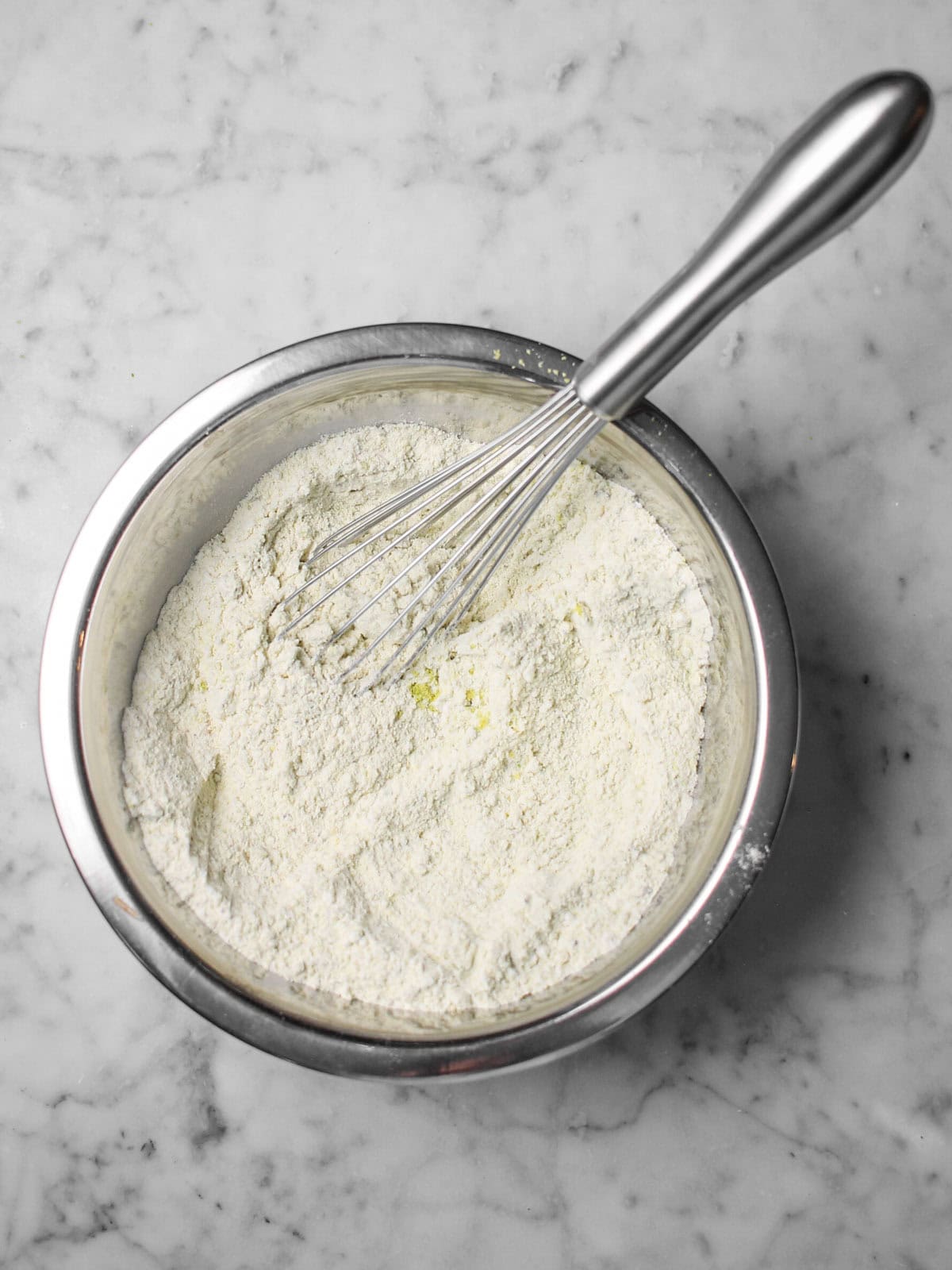 Flour, ground pistachio meal, and baking soda whisked together in a bowl.