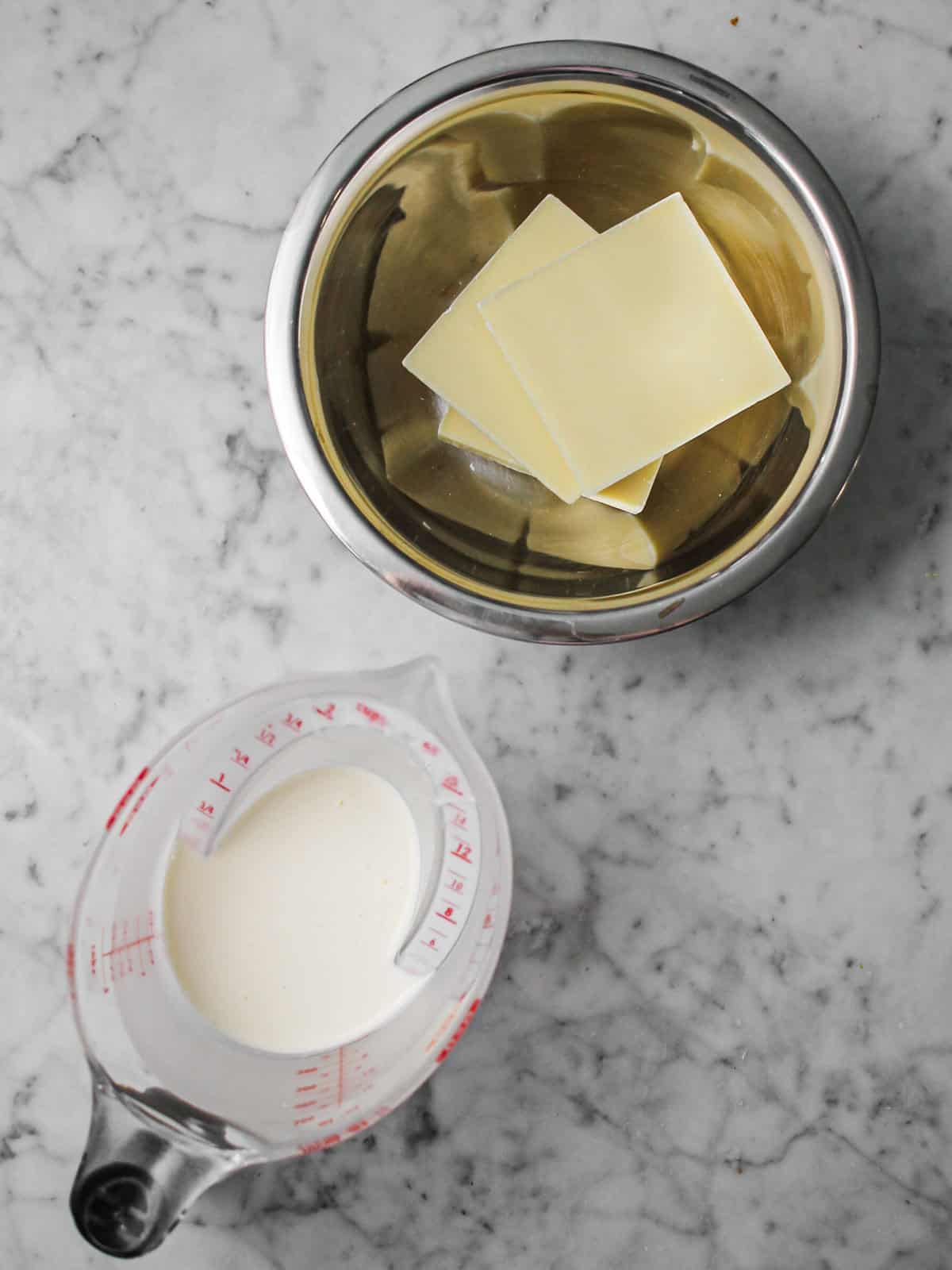 Overhead shot of cream and white chocolate on a countertop in order to make whipped white chocolate ganache.