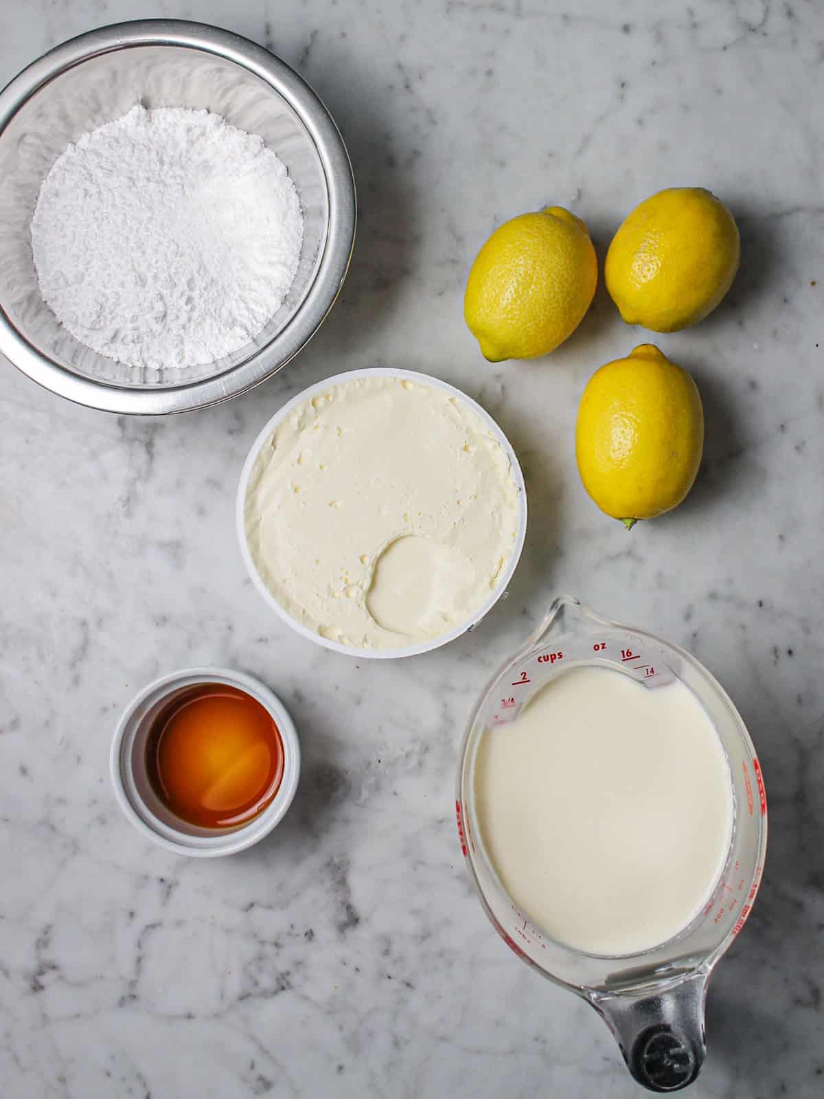 Ingredients for no-bake lemon cheesecake laid out on a countertop.