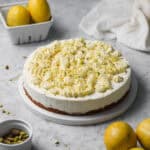No-bake lemon mascarpone cheesecake topped with whipped white chocolate ganache, sitting on a marbled white and gray countertop.