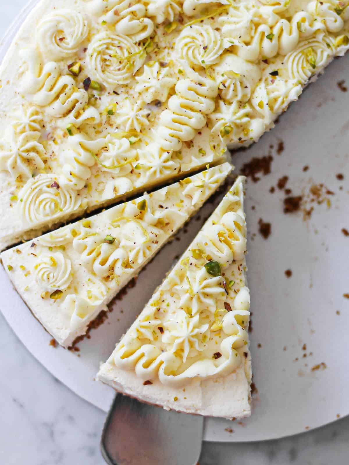 Overhead shot of slices of no-bake lemon mascarpone cheesecake topped with whipped white chocolate ganache.