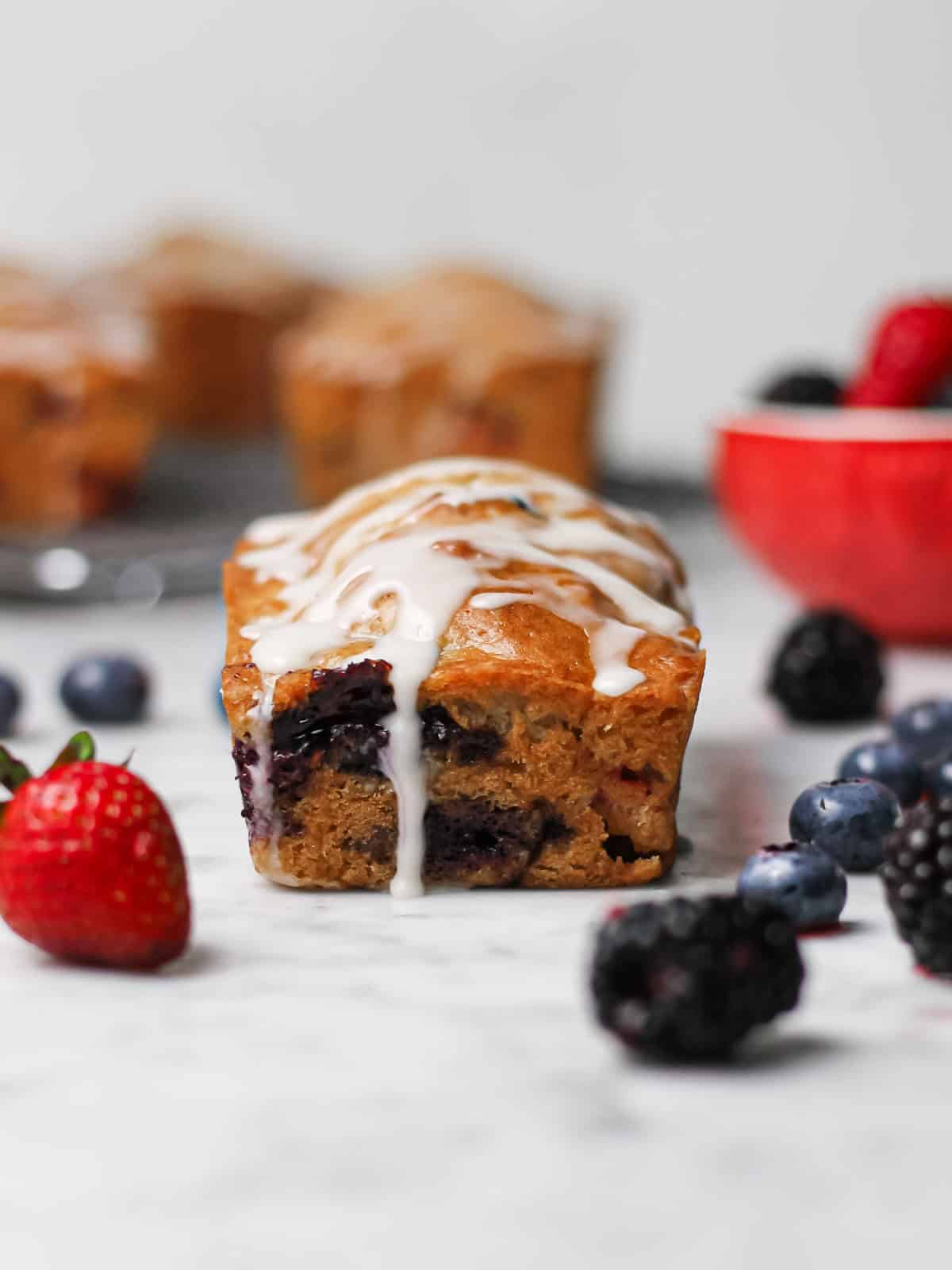 Mini mixed berry loaf cake with fresh berries and vanilla glaze.