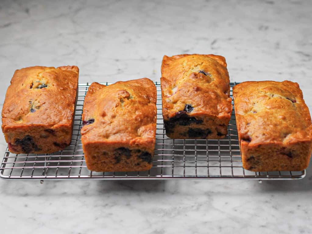 Four baked mini loaves, cooling on a wire rack.