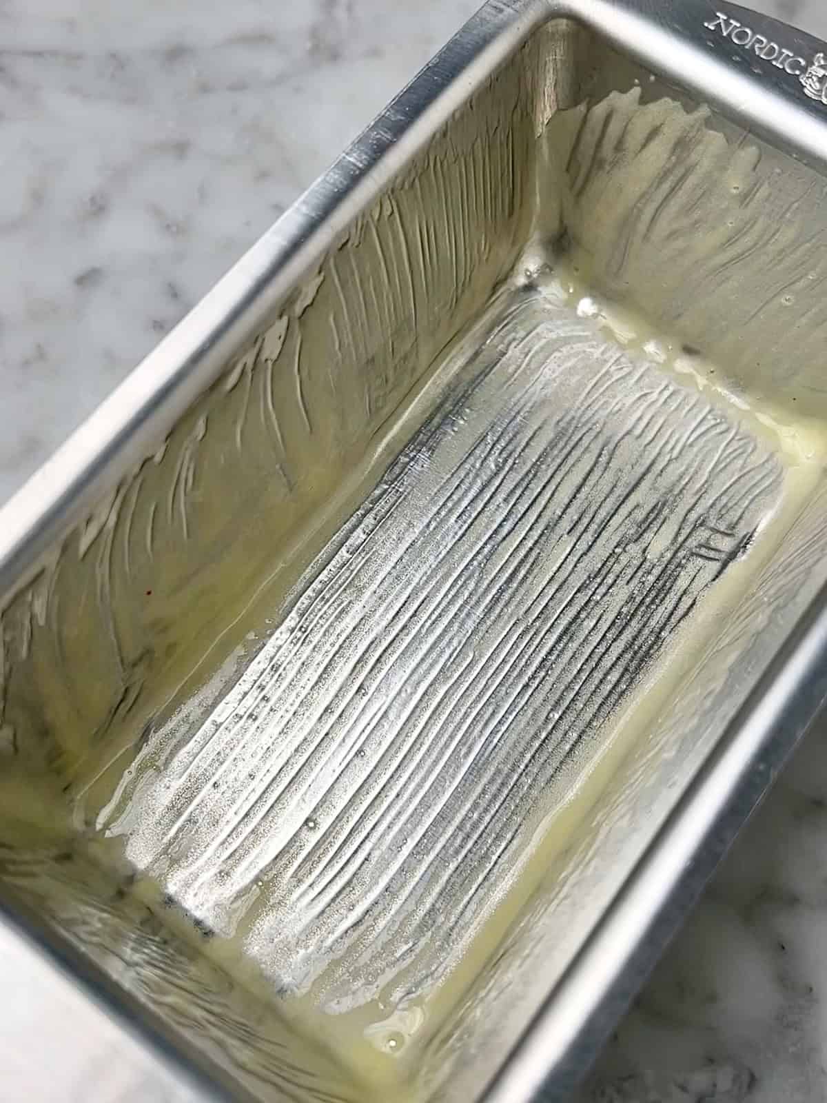 Empty metal baking pan with leftover butter or oil, ready for dessert preparation.