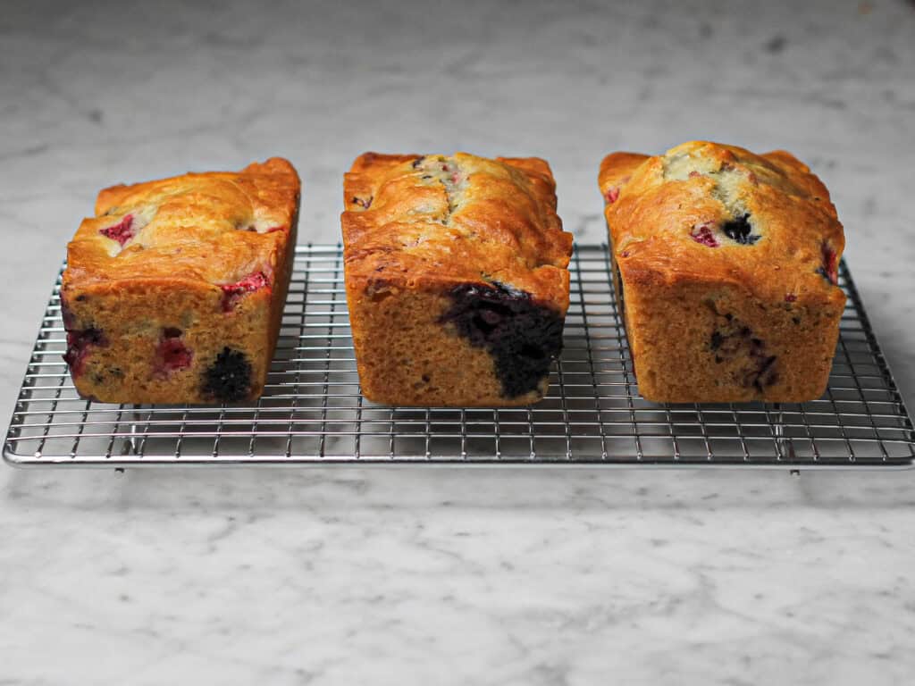 Three baked mini loaves, cooling on a wire rack.