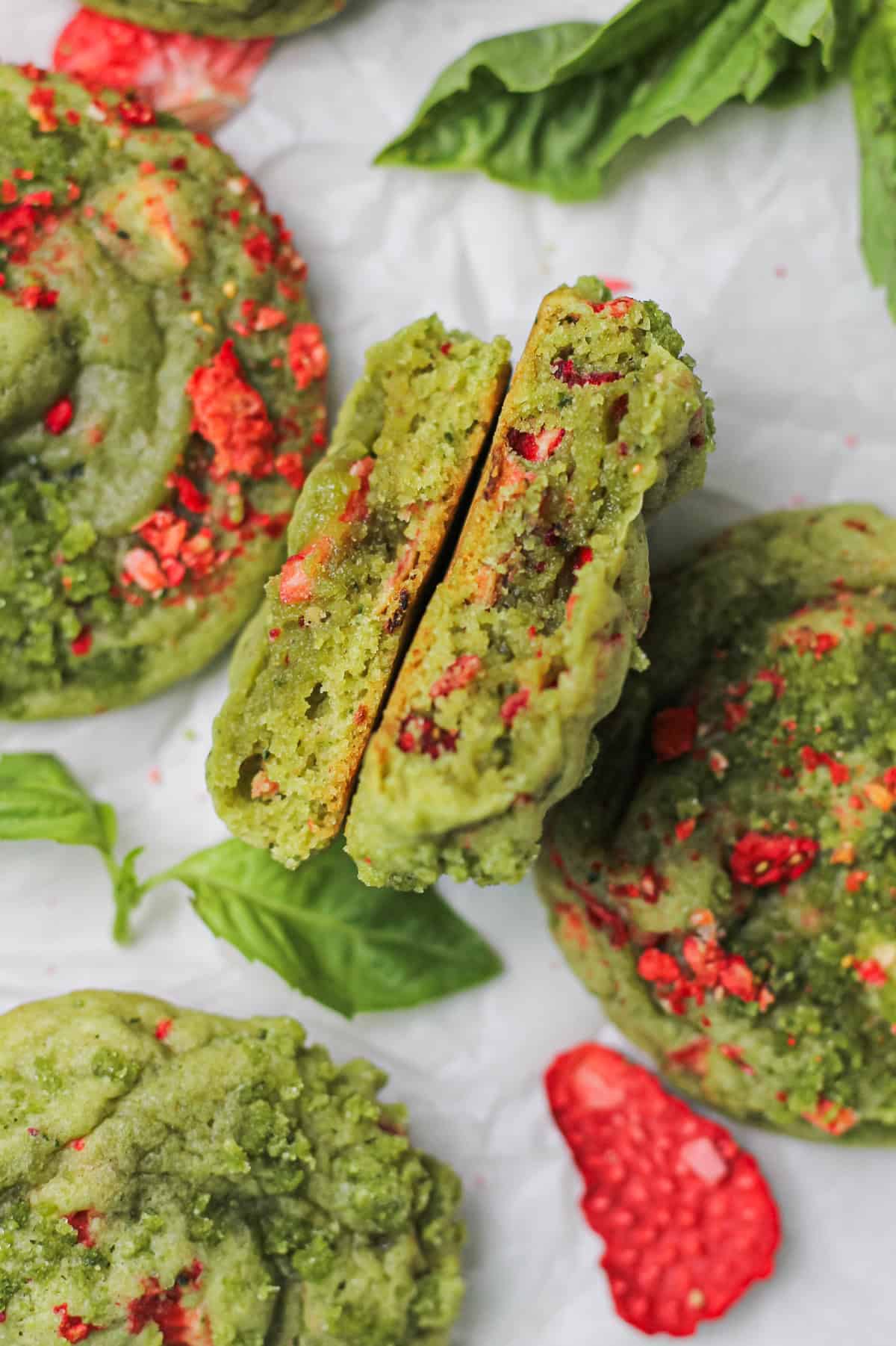 Strawberry basil sugar cookie split in half to reveal the soft and chewy insides, flecked with strawberry pieces.