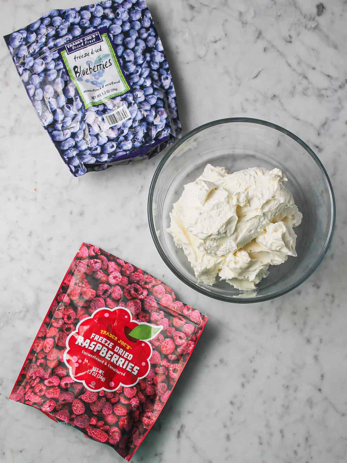 Overhead shot of freeze dried fruit bags next to a container of white frosting.
