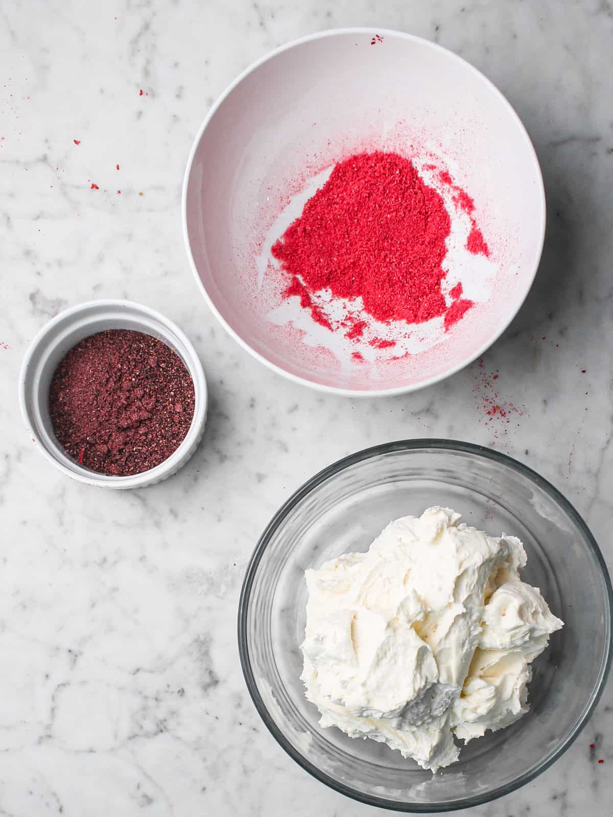Overhead shot of powdered freeze dried fruits next to a container of white frosting.