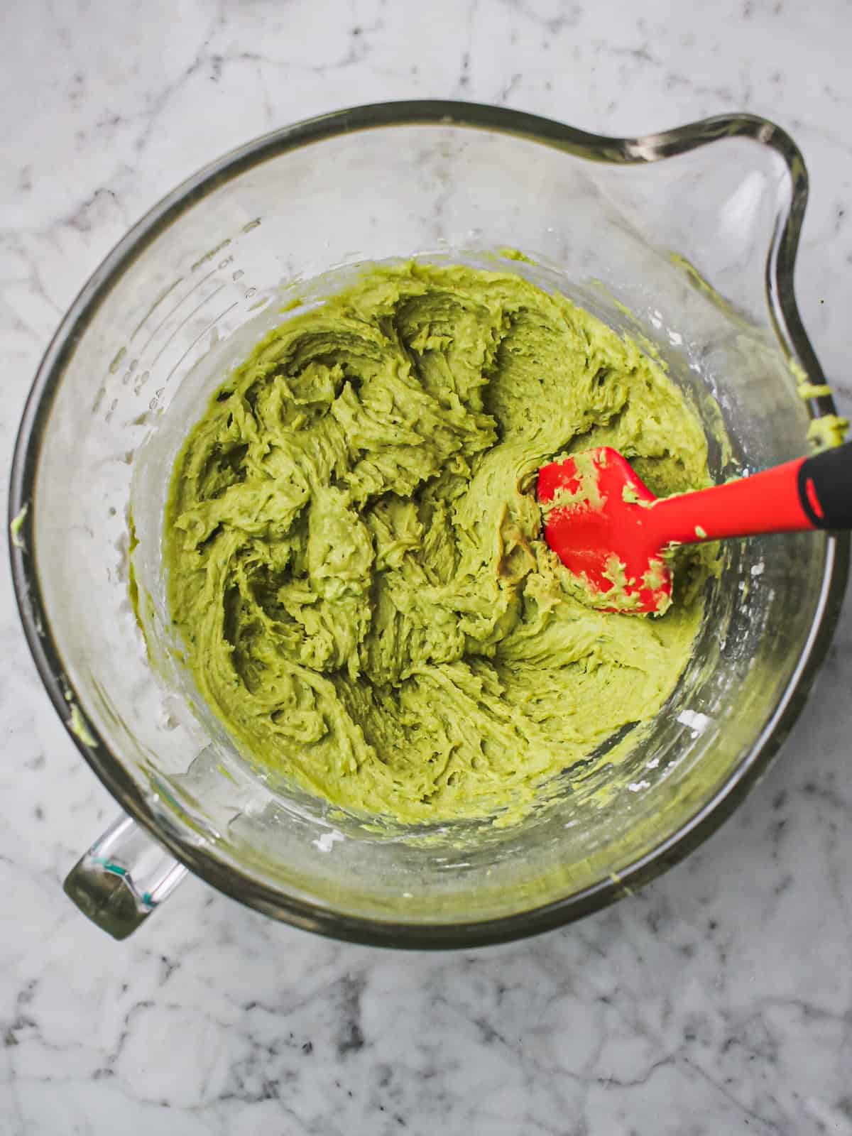 Green dough for basil strawberry sugar cookies in a clear mixing bowl.