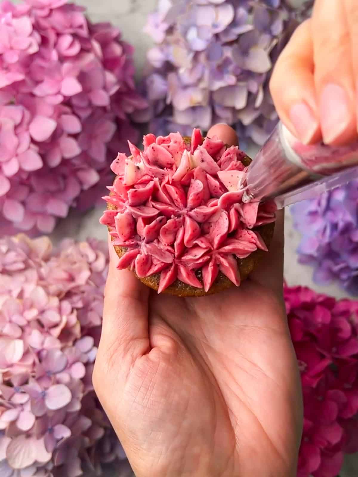 Cupcake covered in piped pink buttercream blooms.