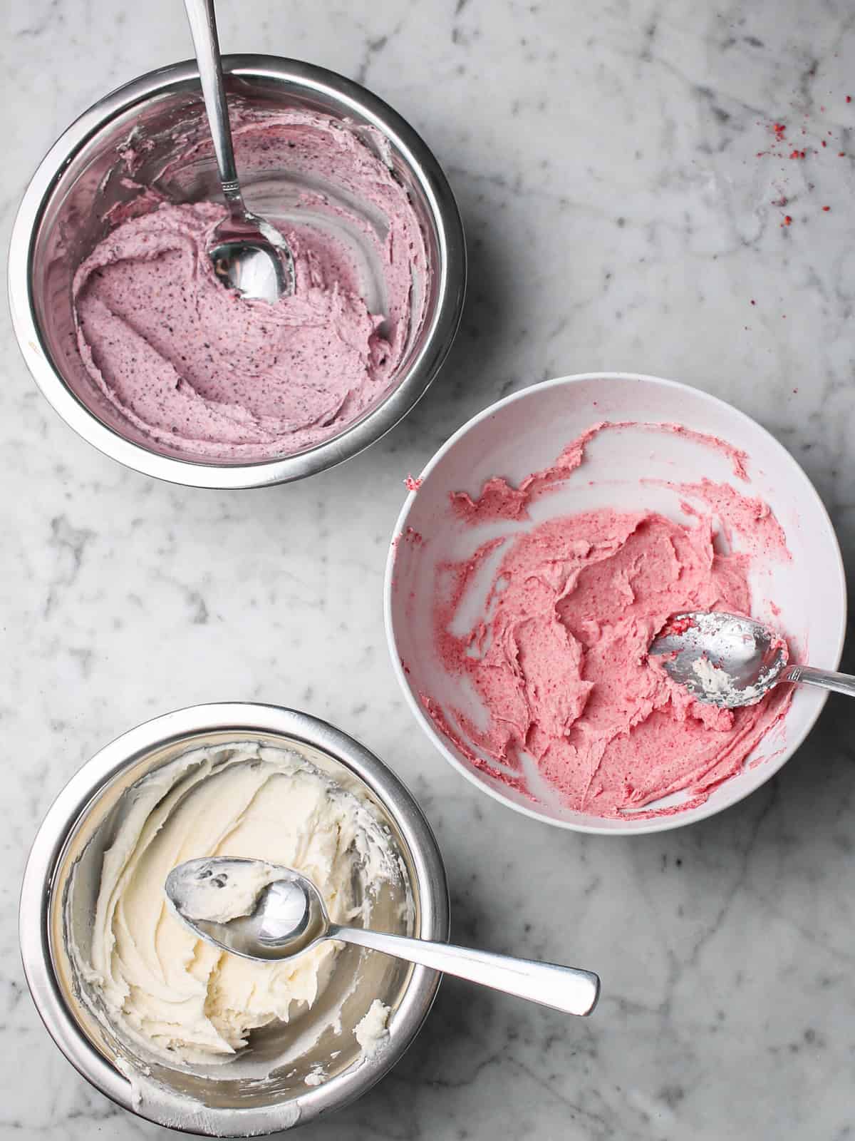 Freeze dried fruits mixed into white frosting to create bowls of purple and pink frosting.