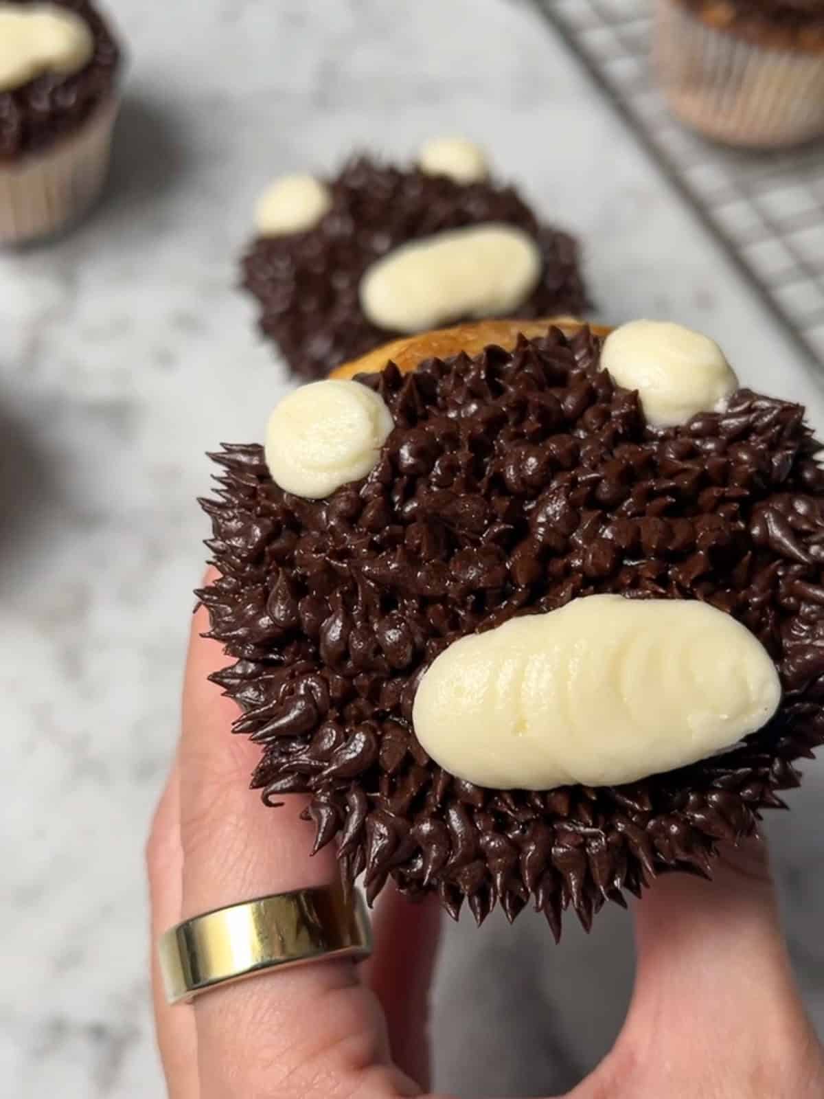 Adding a white buttercream muzzle and ears to a brown teddy bear cupcake.