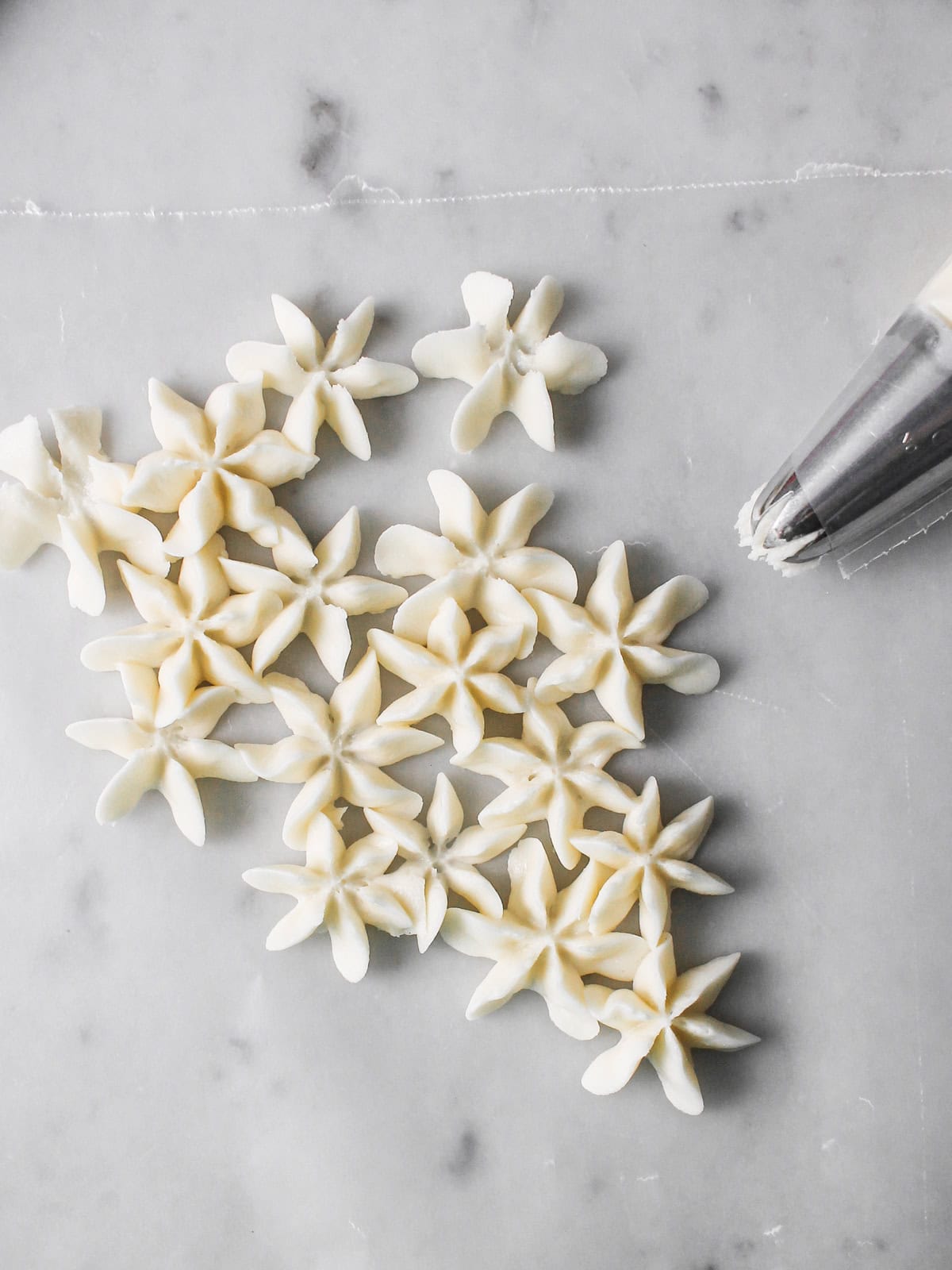Practicing white hydrangea buttercream blooms with a Wilton 2D piping tip on wax paper.