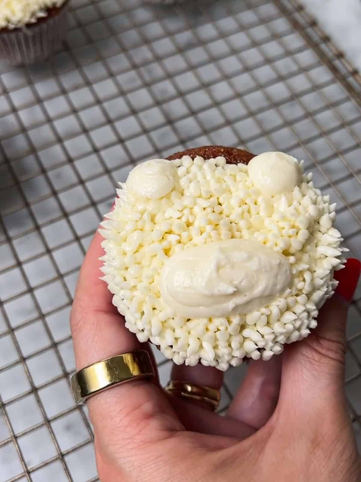 White teddy bear cupcake with rough buttercream on its muzzle.