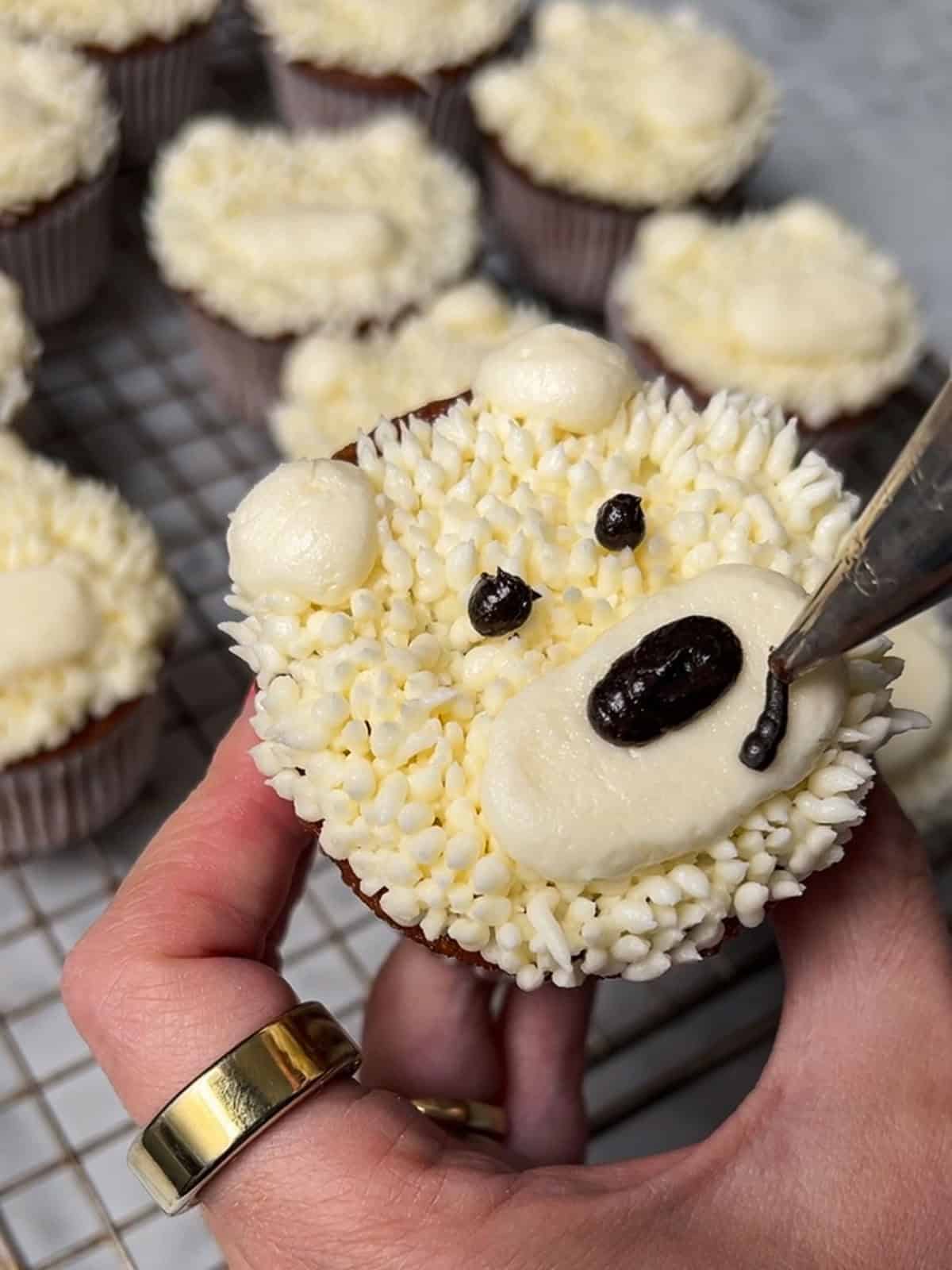 Close-up of a polar bear cupcake with a piped muzzle, mouth, and dark nose.