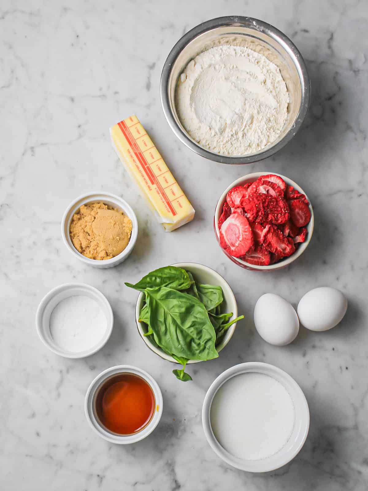 Ingredients for strawberry basil sugar cookies, including fresh basil, freeze-dried strawberries, butter, sugar, and flour.