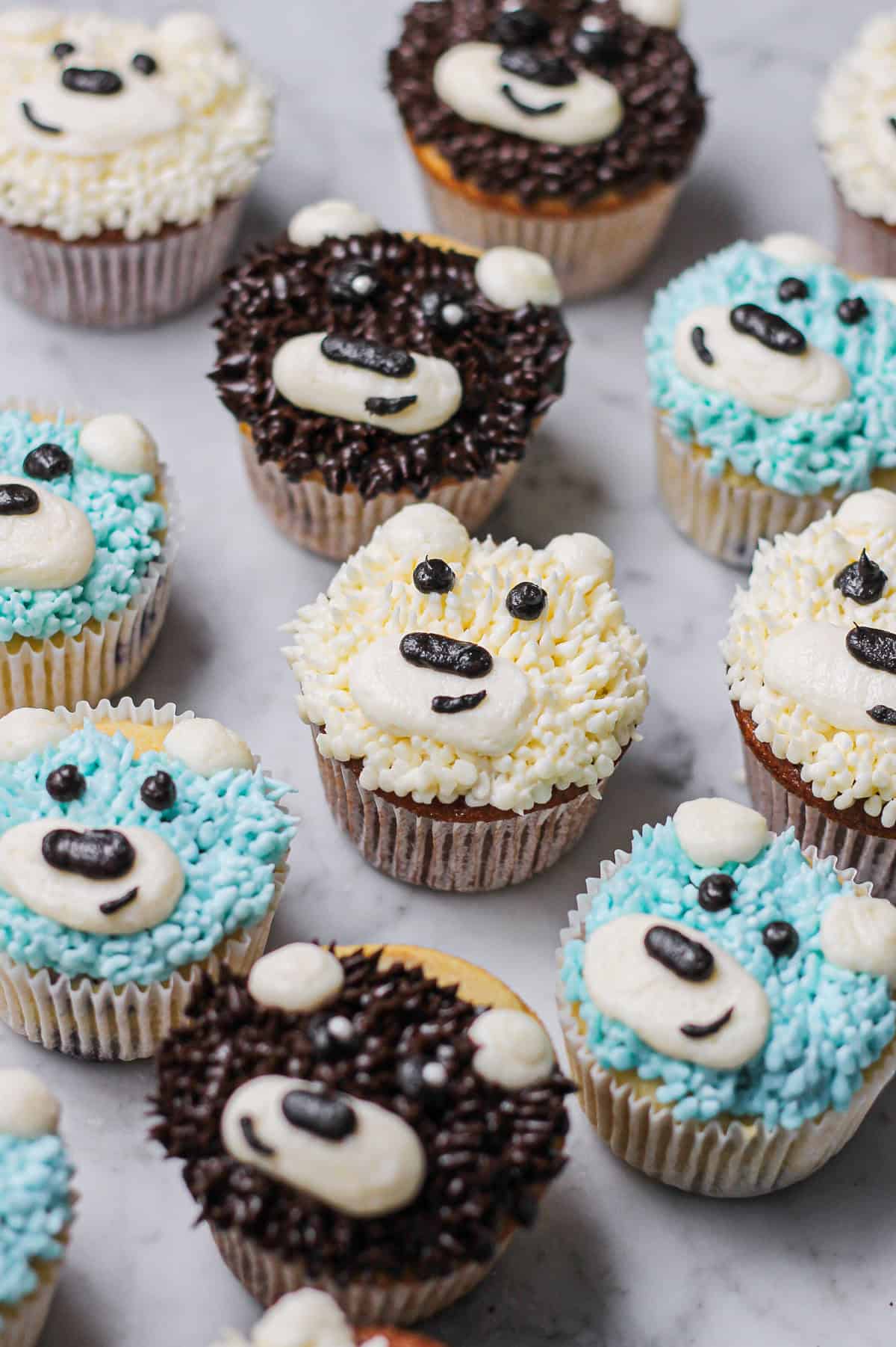 A colorful assortment of piped buttercream bear cupcakes for a party.