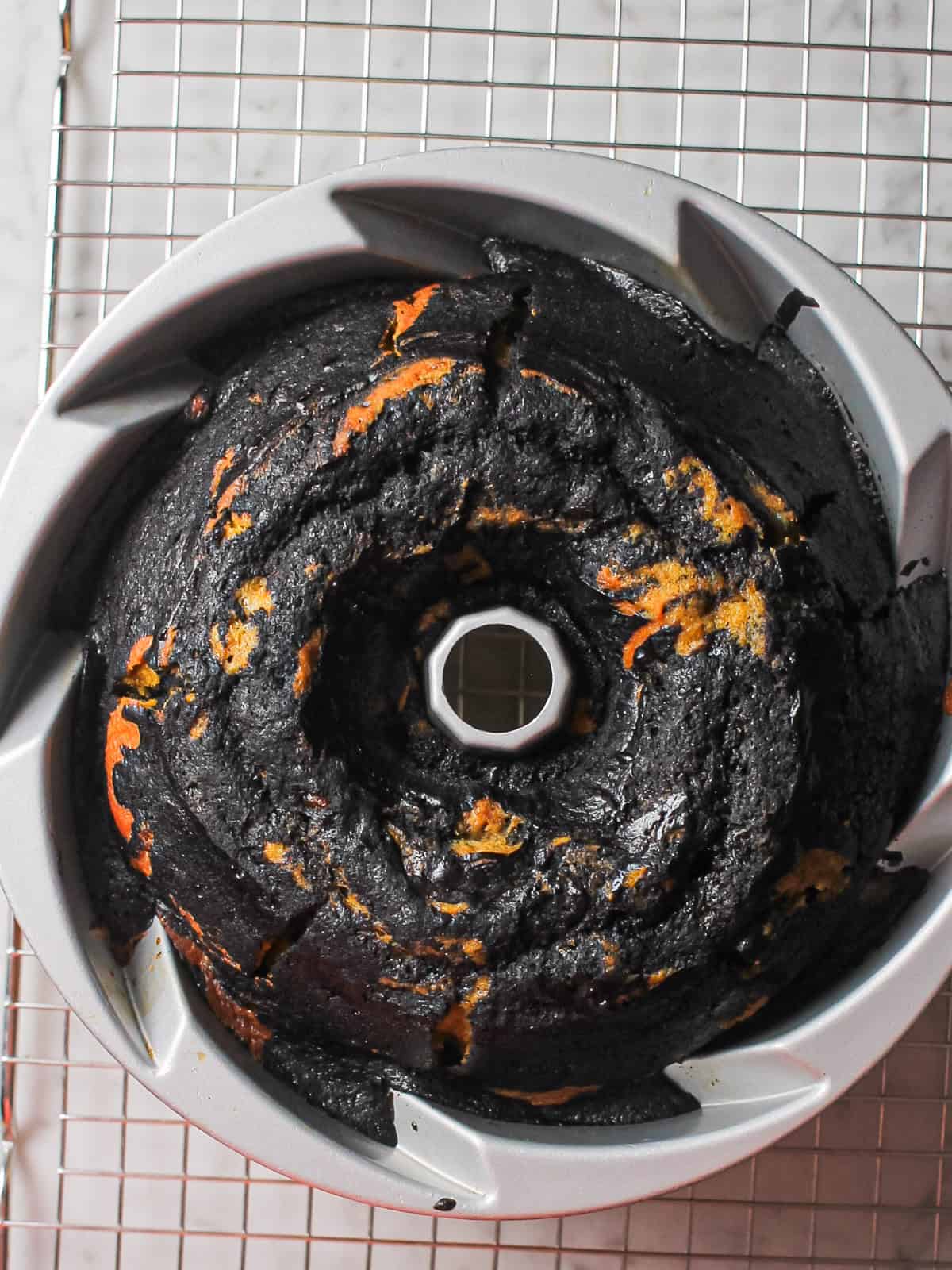 Baked marbled pumpkin Bundt cake cooling in the pan, pulling gently away from the sides.
