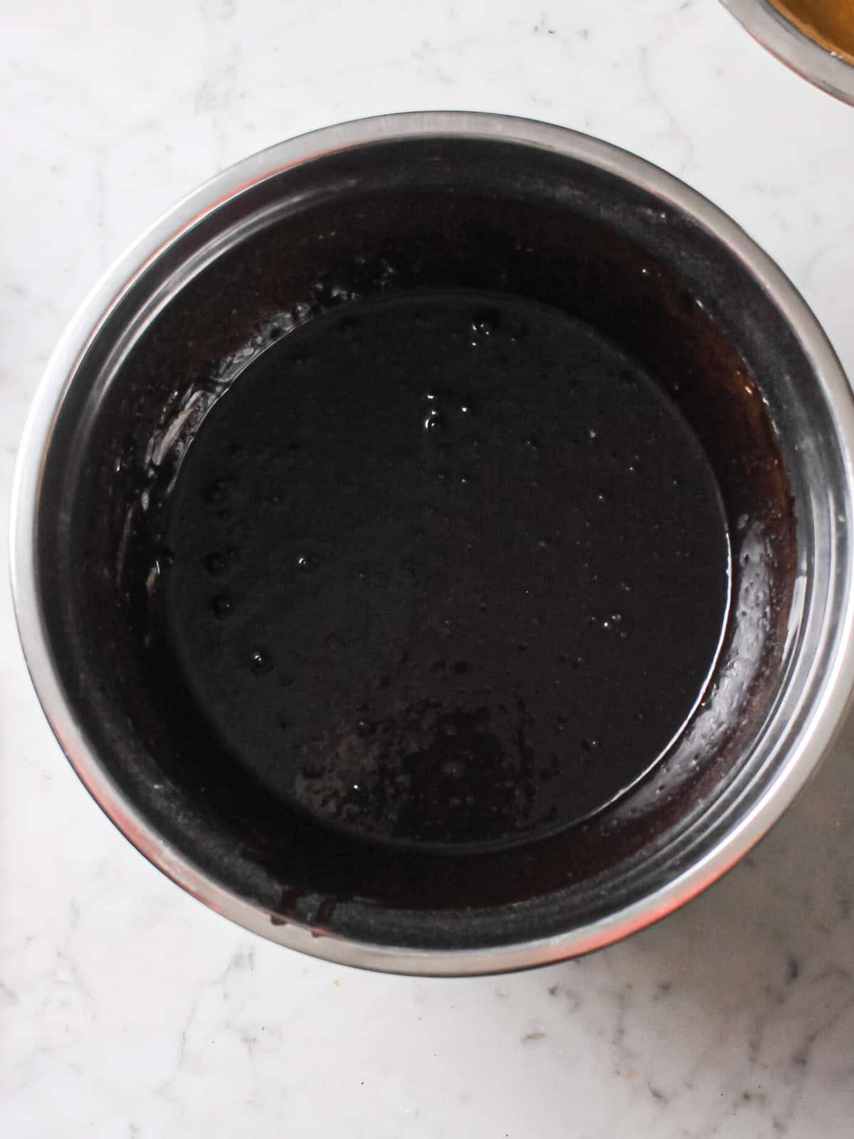 Black cocoa cake batter in a mixing bowl, ready to layer into the pan.