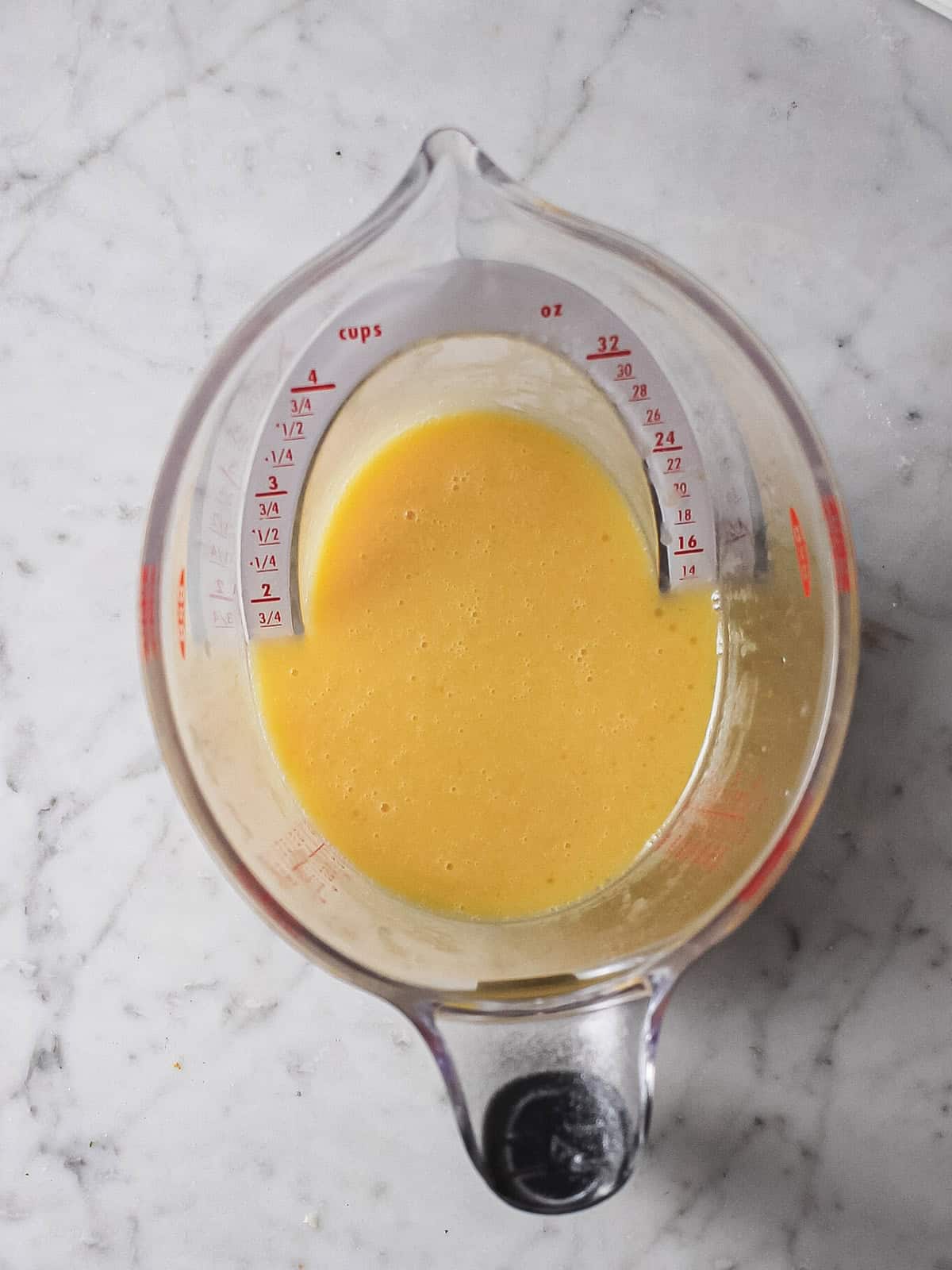 Whisked eggs, oil, and vanilla in a large measuring cup, ready to divide between mixing bowls.