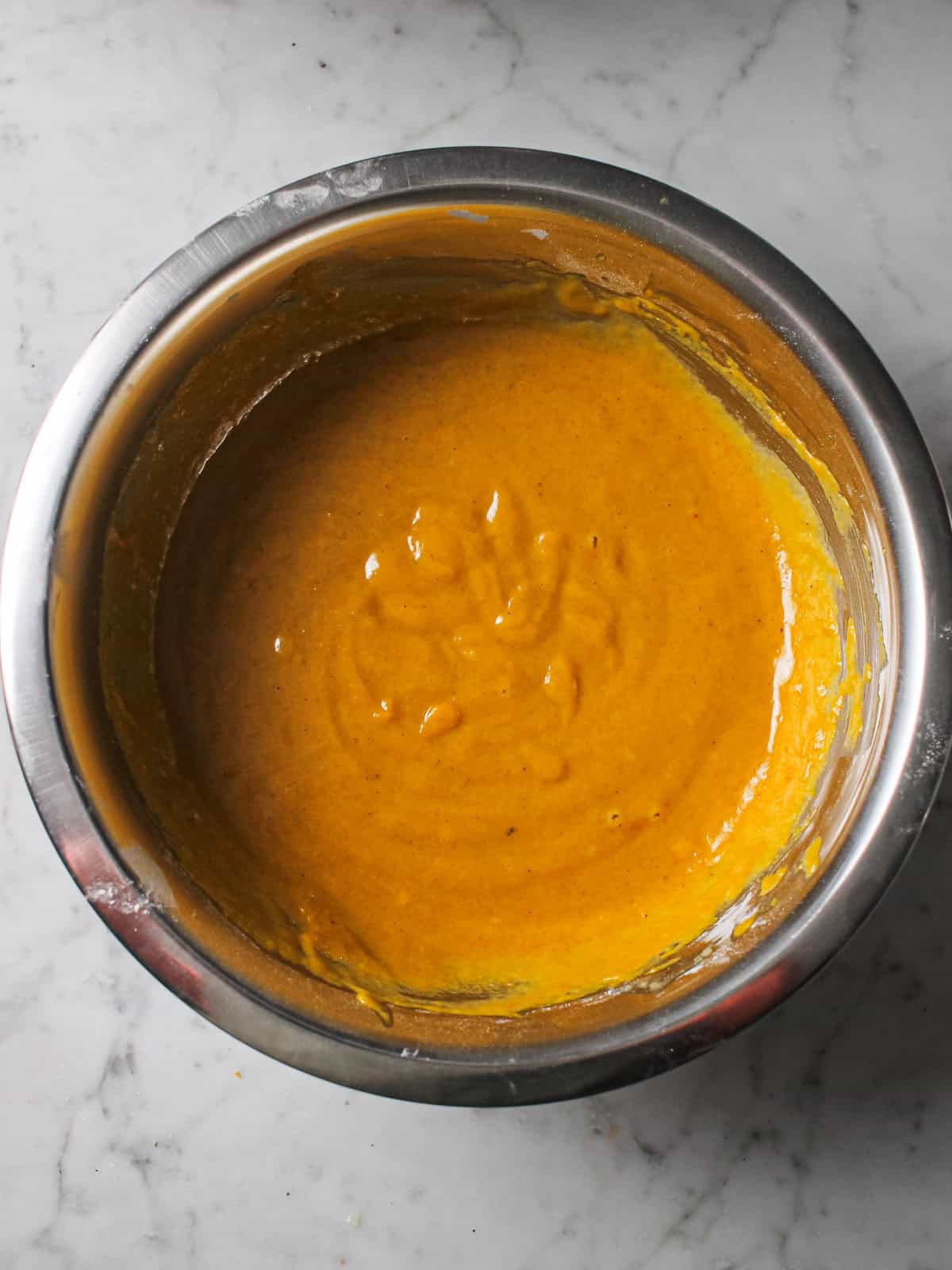 Pumpkin batter in an aluminum mixing bowl.