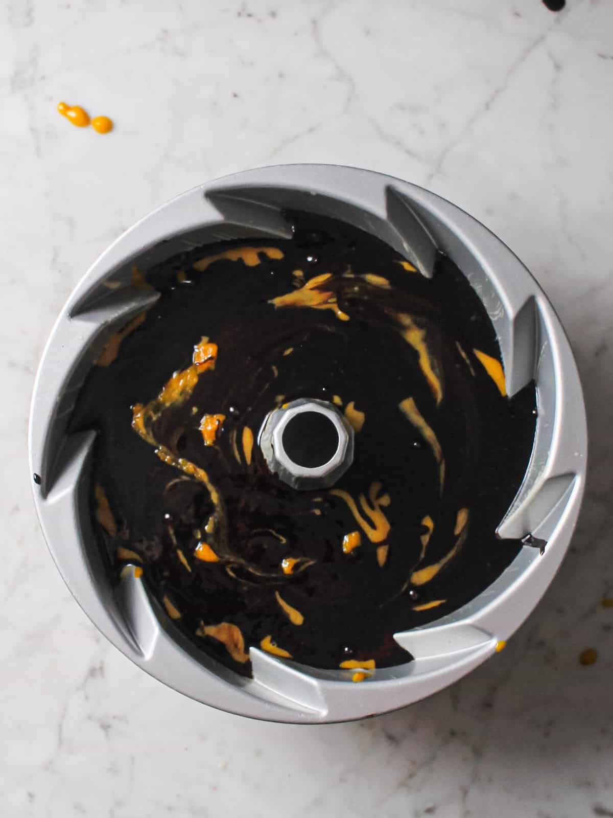 Orange pumpkin and black cocoa batters spooned in alternating dollops and swirled once with a knife in the Bundt pan.